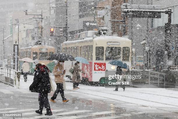 People cross the street as it snows in the city of Toyama, Toyama prefecture on the central-western coast of Japan, on January 24 as parts of the...