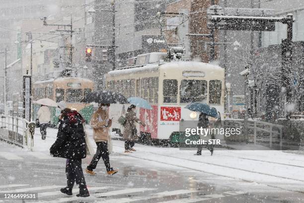 People cross the street as it snows in the city of Toyama, Toyama prefecture on the central-western coast of Japan, on January 24 as parts of the...