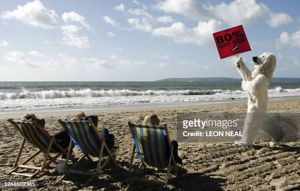 Climate campaigner dressed as a polar bear poses on the beach to demand that the Government cuts carbon dioxide emissions by at least 80 % by 2050 as...