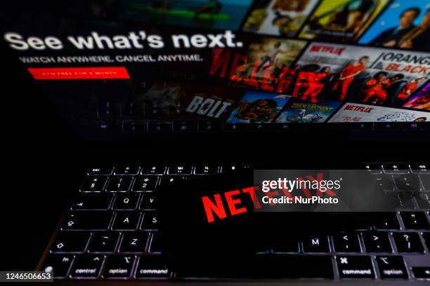 Netflix logo is displayed on a mobile phone screen with Netflix website in a background for illustration photo. Krakow, Poland on January 23, 2023.