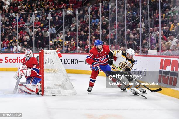 Brad Marchand of the Boston Bruins and Joel Edmundson of the Montreal Canadiens skate after the puck behind the net of goaltender Sam Montembeault...