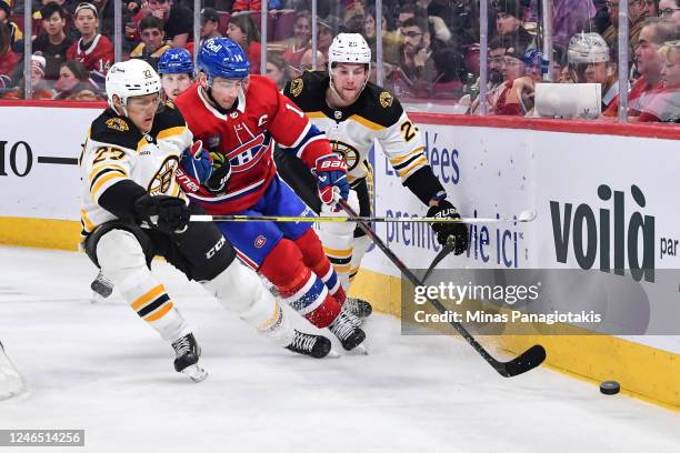Nick Suzuki of the Montreal Canadiens skates in between Hampus Lindholm and Brandon Carlo of the Boston Bruins during the second period of the game...