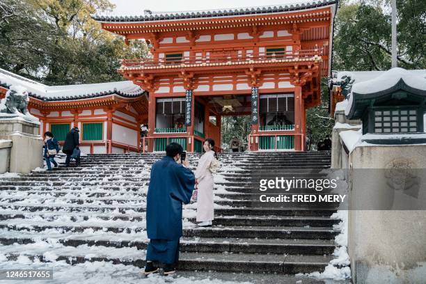 Woman poses for a photo on the snow-covered steps of the Yasaka Shrine in Kyoto on January 25 after heavy snow and strong winds overnight affected...