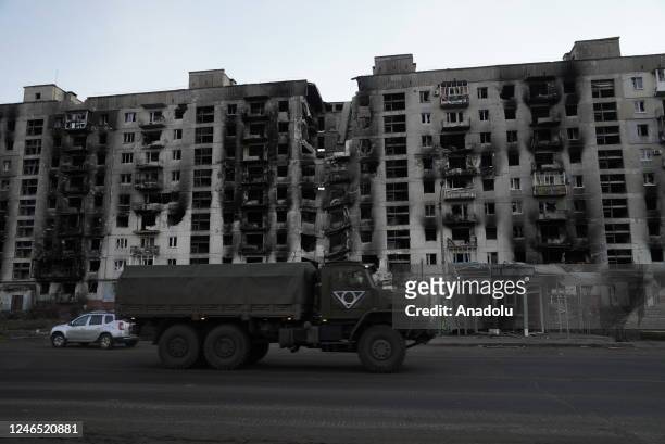 View of a residential building with heavy damage behind a military vehicle in the city most affected by the ongoing war between Russia and Ukraine,...