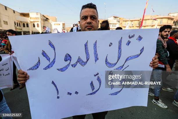 Man stands holding a sign reading in Arabic "depreciate the rate of the [US] dollar, or else..!" during a protest against the depreciation of the...