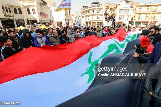 Protesters wave a giant Iraqi national flag during a protest against the depreciation of the Iraqi dinar against the US dollar outside the Central...