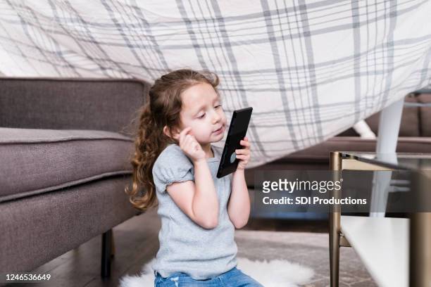 little girl uses smartphone in homemade fort - kids fort stock pictures, royalty-free photos & images