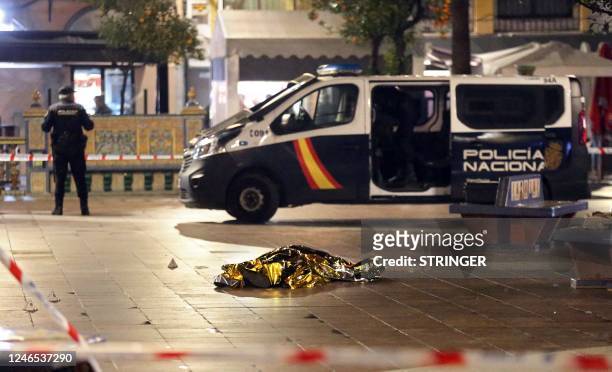 Graphic content / TOPSHOT - The body of a dead man lays on the ground as police secure the area in Algeciras, southern Spain, on January 25, 2023. -...