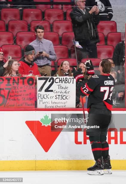 Thomas Chabot of the Ottawa Senators trades a puck for some candy with a fan during warmup prior to a game against the New York Islanders at Canadian...
