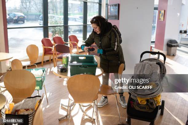 Customer of the Coventry Foodbank centre in Queens Road Baptist Church places the items she needs into bags as she collects her food parcel, in...