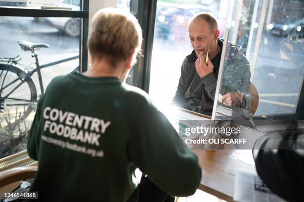 Customer of the Coventry Foodbank centre in Queens Road Baptist Church is registered as he arrives with his foodbank voucher, in Coventry, central...