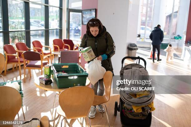 Customer of the Coventry Foodbank centre in Queens Road Baptist Church places the items she needs into bags as she collects her food parcel, in...