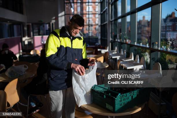 Customer of the Coventry Foodbank centre in Queens Road Baptist Church places the items he needs into bags as he collects his food parcel, in...