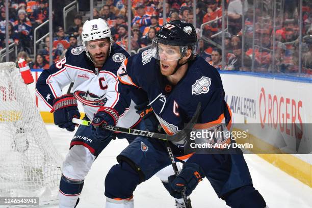 Connor McDavid of the Edmonton Oilers skates with the puck while Boone Jenner of the Columbus Blue Jackets battles for the puck during the game on...