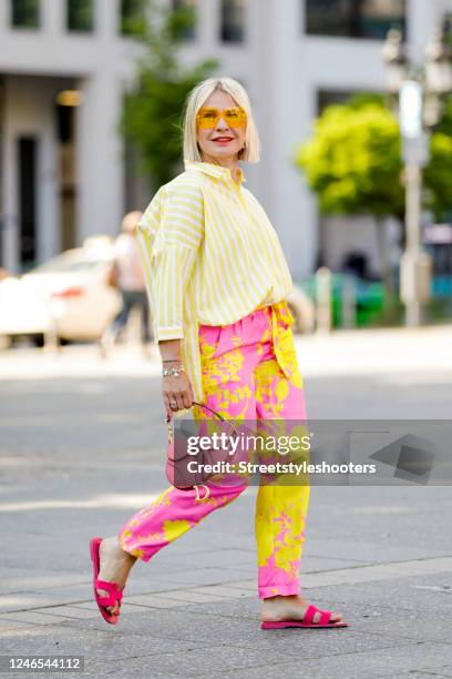 Influencer Simone Adams, wearing a yellow blouse with white stripes by Bailly Diehl, pink pants with yellow pattern by Maison Common Munich, a dark...