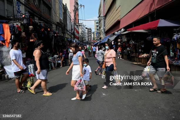 Pedestrians walk as they shop at a market in Manila on January 26, 2022.