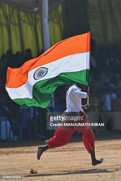 School student runs with a flag of India during celebrations for the India's 74th Republic Day in Bengaluru on January 26, 2023.
