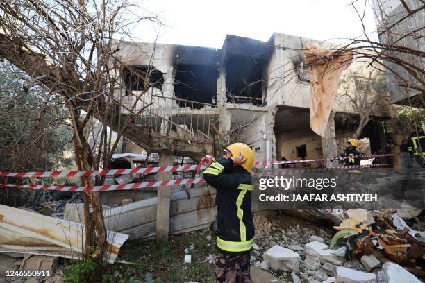 Graphic content / A rescuer is pictured in front of a building damaged and burned by Israeli troops during a raid on the West Bank's Jenin refugee...