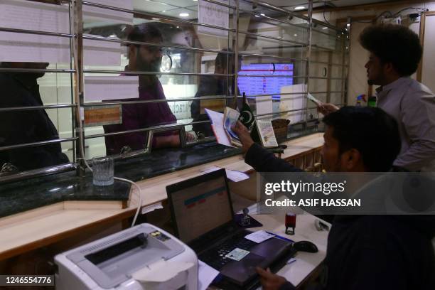 Customers exchange currency at a money exchange market in Karachi on January 26, 2023. - The Pakistani rupee dived to an historic low against the US...