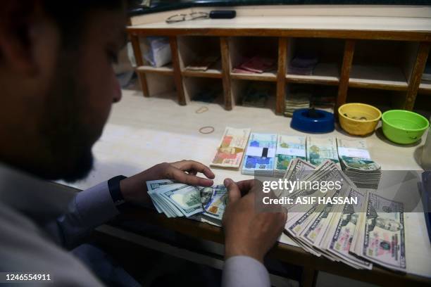 Dealer counts US dollars at a money exchange market in Karachi on January 26, 2023. - The Pakistani rupee dived to an historic low against the US...