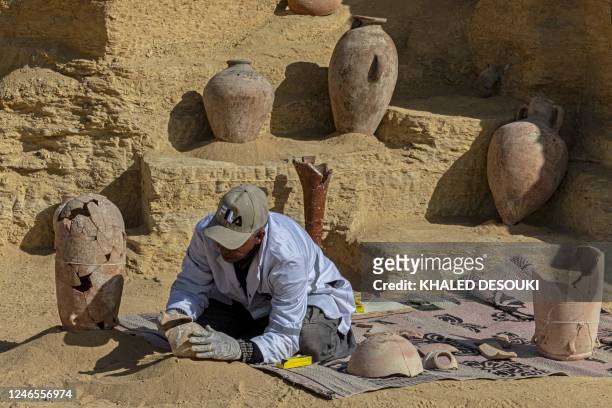 An Egyptian archaeologist restores antiquities at the Saqqara archaeological site, where a gold-laced mummy and four tombs including of an ancient...