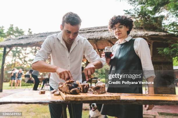 vrienden die barbecuevlees snijden - argentina friendly stockfoto's en -beelden