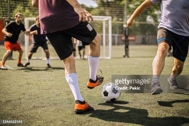 jugador de fútbol masculino pateando pelota de fútbol - playing football fotografías e imágenes de stock
