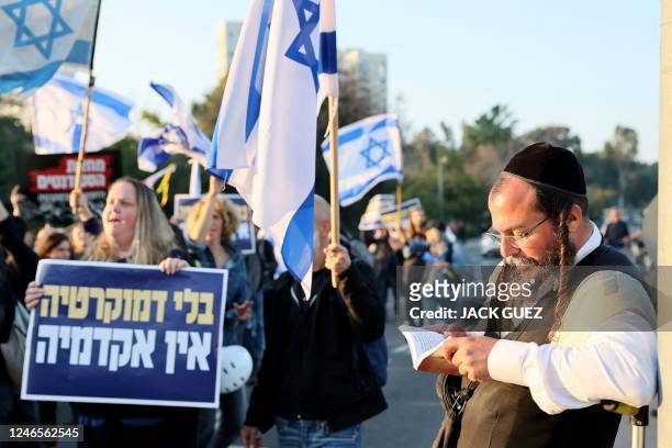 Israeli protesters shout slogans during a demonstration against controversial government plans to give lawmakers more control of the judicial system,...