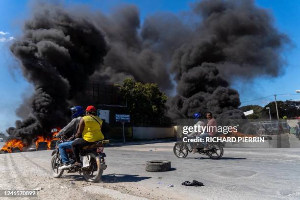 Motorcyclists drive by burning tires during a police demonstration after a gang attack on a police station which left six officers dead, in...