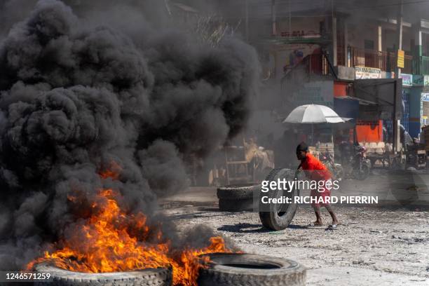 Protestor adds a tire to a burning barricade during a police demonstration to protest the recent killings of six police officers by armed gangs, in...