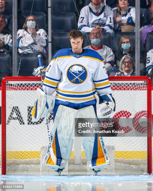 Goaltender Eric Comrie of the Buffalo Sabres looks on from the crease prior to puck drop against the Winnipeg Jets at the Canada Life Centre on...