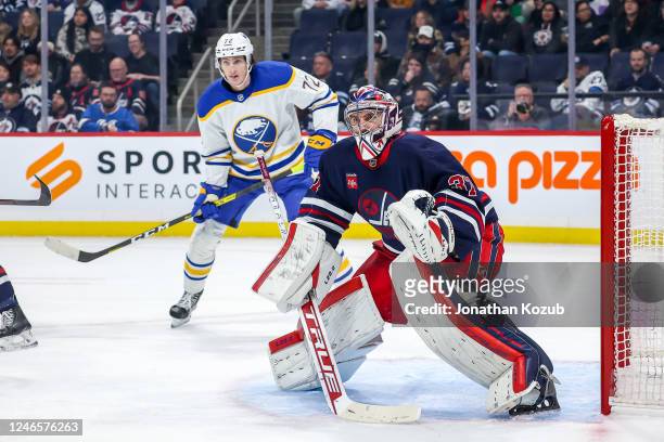 Goaltender Connor Hellebuyck of the Winnipeg Jets and Tage Thompson of the Buffalo Sabres keep an eye on the play during first period action at the...