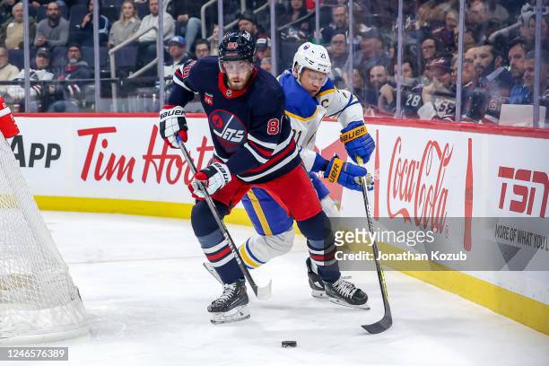 Pierre-Luc Dubois of the Winnipeg Jets plays the puck around the net as Kyle Okposo of the Buffalo Sabres gives chase during first period action at...