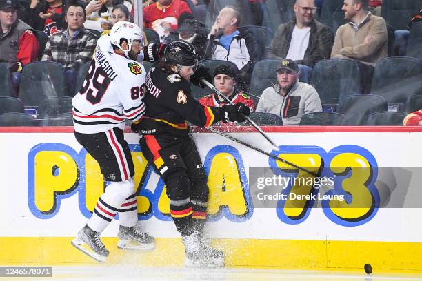 Andreas Athanasiou of the Chicago Blackhawks collides with Rasmus Andersson of the Calgary Flames during the second period of an NHL game at...