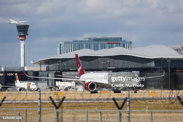 Virgin Atlantic Airways Airbus A350-1000 aircraft as seen taxiing infront of other planes, the air traffic control tower, the gates of the terminal...