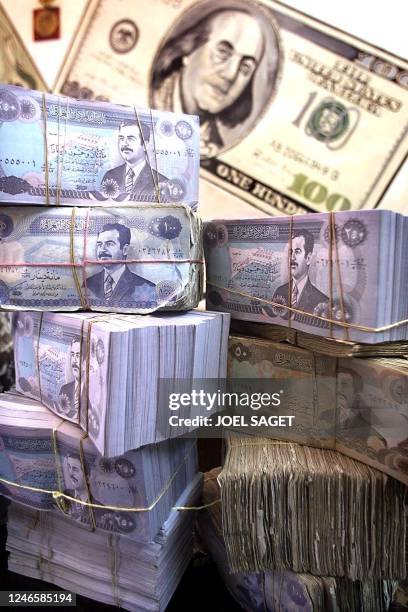 Wads of Iraqi dinars are placed under a picture of a 100 US dollar bill on the desk of an Iraqi money changer in Baghdad 20 January. - Before Iraq's...