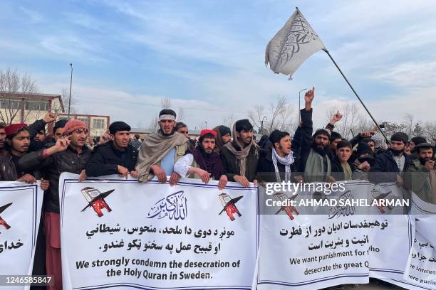 Men hold banners and shout slogans during a protest after Friday prayers against the burning of the Koran by Swedish-Danish far-right politician...