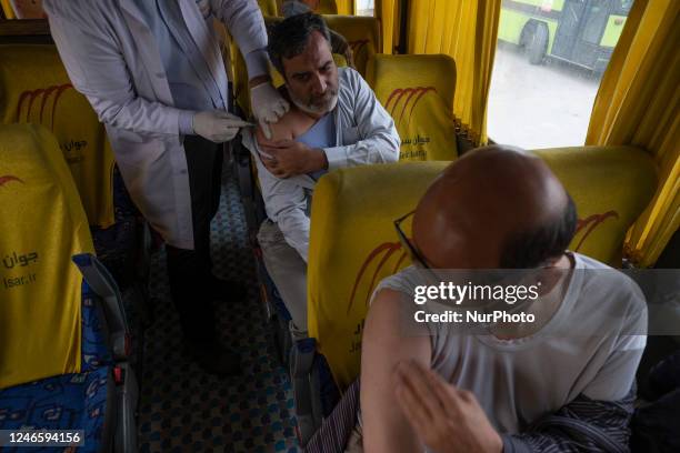 An Iranian worshipper receives a dose of the Iranian Noora new coronavirus disease vaccine at a mobile vaccination station during Tehran's Friday...