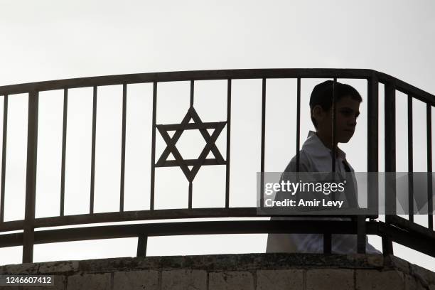 An Orthodox Jewish child stands on a synagogue roof near the scene of a mass shooting which happened last night near a synagogue in the neighbourhood...