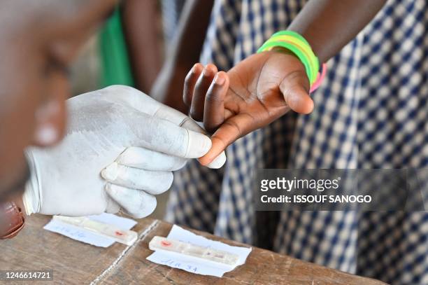 Doctor draws blood from a child during screening campaign against leprosy in village of Djougbosso, near Adzope, on January 25, 2023. - Listed by the...