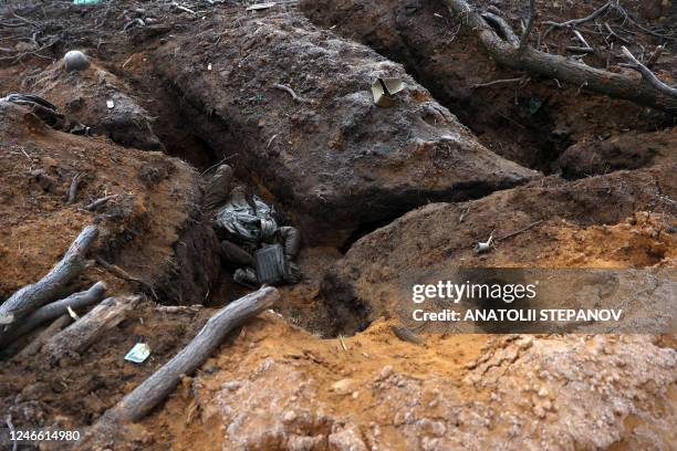 Graphic content / This photograph taken on January 28, 2023 shows the body of a Russian soldier lying in a trench on the frontline near the town of...