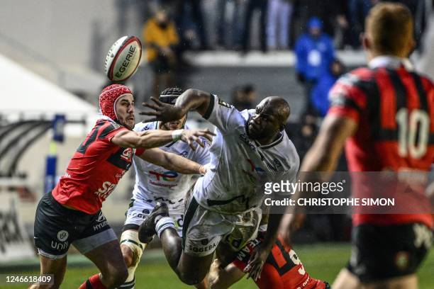 Pau's French back row Jordan Joseph passes the ball as he is tackled by Toulon's French wing Gabin Villiere during the French Top 14 rugby union...