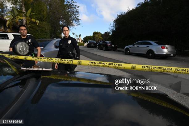 Police officers secure the crime scene as they await investigators after an early morning shooting that left three people dead and four wounded in...