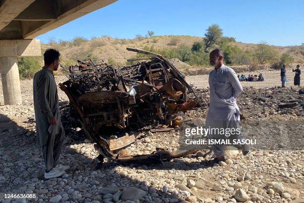 Residents look at the wreckage of a burnt passenger bus in Lasbela district of Pakistan's Balochistan province on January 29, 2023. - At least 40...