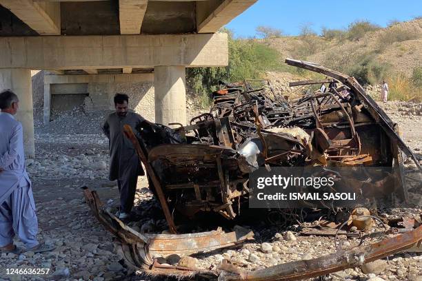 Residents look at the wreckage of a burnt passenger bus in Lasbela district of Pakistan's Balochistan province on January 29, 2023. - At least 40...