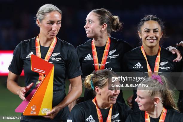 New Zealand's players celebrate with the trophy after winning the women's competition in the World Rugby Sevens series, at the Allianz Stadium in...