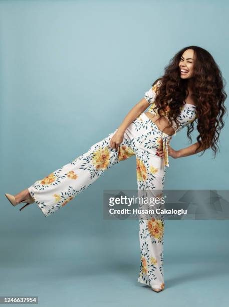 beautiful woman with long curly hair in floral outfit front of blue background - fashion stock pictures, royalty-free photos & images