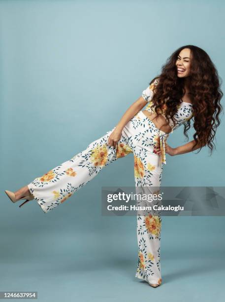 beautiful woman with long curly hair in floral outfit front of blue background - summer clothing stock pictures, royalty-free photos & images