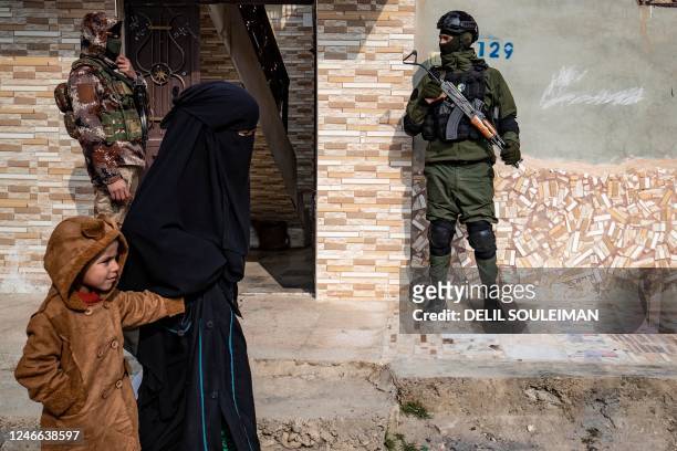 Syrian Kurdish Asayish security forces stand guard outside a house during a raid against suspected Islamic State group fighters in Raqa, the jihadist...