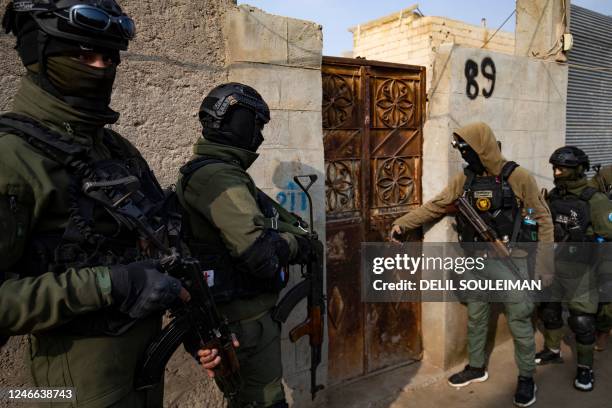 Syrian Kurdish Asayish security forces knock on the door of a house during a raid against suspected Islamic State group fighters in Raqa, the...